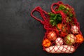 Eco friendly reusable mesh string bag with fresh organic vegetables on black background. Zero waste shopping concept