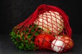 Eco friendly reusable mesh string bag with fresh organic vegetables on black background. Alternative to plastic bags Royalty Free Stock Photo