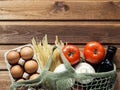 Eco friendly reusable shopping bag filled with eggs, pasta, tomato, mushrooms and oil on wooden background. Eco concept