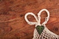 Eco friendly string bag and green leaf on wooden background, responsible consumption. zero waste concept.