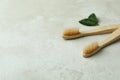 Eco friendly toothbrushes and leaves on white textured background