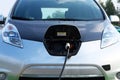 Eco friendly transport concept. Loading energy. Gray car is charged on electric charging station in parking. Close up Royalty Free Stock Photo