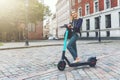 eco friendly transport - young business woman rides electric scooter in the city streets