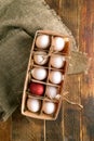 Eco-friendly wooden box with white eggs and one red Easter egg on burlap on old wooden table. Royalty Free Stock Photo