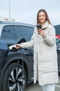 Young woman charging her electric car at a charging station in the city