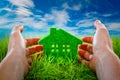 Eco House in green grass protected by the human hands Royalty Free Stock Photo