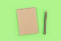 Eco natural mockup with craft recycled paper notepad and pen in the form of a tree trunk with bark on green background. Spring