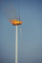 Eco power windturbine at sunny day under fire. Fire flames and black smoke escaping outside