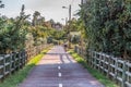 Eco view pedestrian / cycle lane, with cyclist pedaling and agricultural fields, trees and house as background Royalty Free Stock Photo