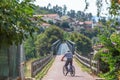 Eco view pedestrian / cycle lane, with senior man cycling and pedaling, wooden barrier on edges, metallic bridge and a village as