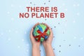 Ecological concept with globe in hands on blue background and text. There is no planet B.