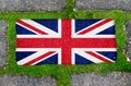 On the sidewalk in green moss, paving slabs with the image of the flag of Great Britain. Royalty Free Stock Photo