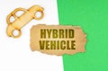 On a white-green surface, a car and a cardboard sign with the inscription - Hybrid Vehicle Royalty Free Stock Photo