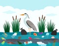 Ecological disaster of plastic waste in the river. A heron bird stands in a lake polluted with plastic debris and dead Royalty Free Stock Photo