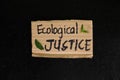 Ecological justice concept. Carton placard with handwritten message in dark black background. Royalty Free Stock Photo
