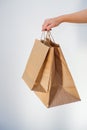 Ecological packaging. A cute unrecognizable woman hands you eco bags made of recycled paper. Shopping concept, natural materials, Royalty Free Stock Photo