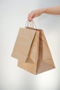 Ecological packaging. A cute unrecognizable woman hands you eco bags made of recycled paper. Shopping concept, natural materials, Royalty Free Stock Photo