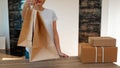 Ecological packaging. A cute unrecognizable woman hands you eco bags made of recycled paper. Shopping concept, natural materials, Royalty Free Stock Photo
