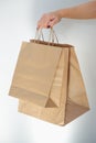 Ecological packaging. A cute unrecognizable woman hands you eco bags made of recycled paper. Shopping concept, natural materials, Royalty Free Stock Photo