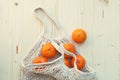 White eco-friendly string bag with fruits, oranges on wooden background, plastic free shopping