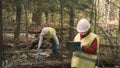 Ecologist man in workwear and helmet measures diameter of plastic dump Royalty Free Stock Photo