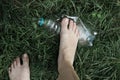 Ecology concept. Human foot crushes a plastic bottle on grass. Royalty Free Stock Photo