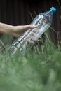 Ecology concept. Person throws a plastic bottle into the grass