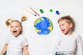 Ecology concept with two prety little kids painting earth on white background