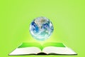 Planet earth globe floating over opened book with green background. Elements of this image furnished by NASA.