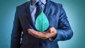 Ecology and Green Energy concept with businessman in a blue suit holding green leaf in his hands