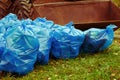 Pile of blue trash bags filled with garbage on the grass and the tractor bucket Royalty Free Stock Photo