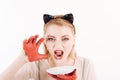 Ecology product and heath. Cat woman eat sour cream. Girl in kitten ears and red gloves with yoghurt isolated on white Royalty Free Stock Photo