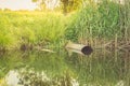 Ecology subject: sewer pours out waste to the lake/sewage from the sewer pollutes a lake Royalty Free Stock Photo