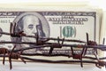 Economic warfare, sanctions and embargo busting concept. Close up US Dollar banknotes wrapped in barbed wire