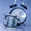 Economic warfare, sanctions and embargo busting concept. US Dollar money wrapped in barbed wire and alarm clock Royalty Free Stock Photo