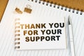On the table there is a pen, clamps and a notebook with the inscription - THANK YOU FOR YOUR SUPPORT Royalty Free Stock Photo