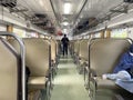 Economy class train interior with two rows of seats with passengers sitting inside