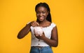 Economy Concept. Smiling Black Woman Holding And Inserting Coin At Piggy Bank