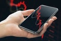 Economy crisis and mobile trading concept with falling down red financial chart candlestick on smartphone screen in human hand on