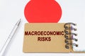 On the flag of Japan lies a pen and a notebook with the inscription - macroeconomic risks