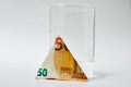 Economy. Increasing the cost of water is a concept. 50 euro banknote folded in triangle next to glass filled with