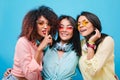 Ecstatic asian girl in blue cotton shirt embracing friends during photoshoot. Indoor portrait of catching african lady Royalty Free Stock Photo