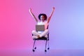 Ecstatic black lady celebrating with arms up in front of laptop on pink and purple background Royalty Free Stock Photo