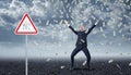 Ecstatic businessman standing under many dollar bills falling from the sky with a traffic warning sign `Money` nearby. Royalty Free Stock Photo