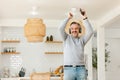 Ecstatic excited grey-haired man in casual and wireless headphones enjoy spare time, listen favorite music and dancing in front