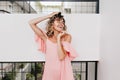 Ecstatic girl in summer pink dress posing with eyes closed. Portrait of elegant tanned female model