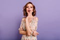 Ecstatic glamorous woman with trendy makeup enjoying photoshoot on purple background. Indoor photo of cute european girl