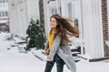 Ecstatic smiling girl with long hair waving, hurrying somewhere in winter day. Good-looking young woman in trendy attire