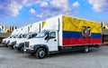 Ecuador flag on the back of Five new white trucks against the backdrop of the river and the city. Truck, transport, freight