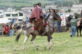 Ecuadorian cowboy wearing furry chaps and wool poncho on horseback